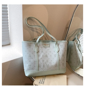 Detail of light green tote bag with bunny monogram print and brand logo in mirror reflection