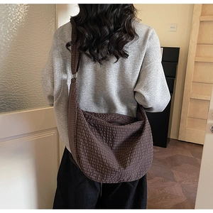 Detail of dark brown checkered crossbody bag with adjustable strap on a model