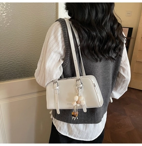 Detail of white vintage shoulder bag featuring flower charm and pearl bead accents