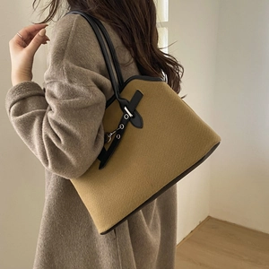 Detail of mustard wool tote bag with black leather straps and metal eyelet accents