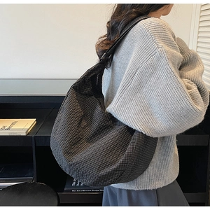 Detail of a large checkered hobo bag featuring durable fabric and a wide shoulder strap