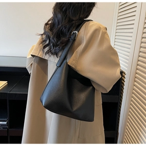 Detailed close-up of premium black lychee leather texture and silver buckle on a hobo bag