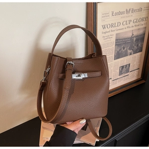 Detail of lychee pattern leather bucket bag with silver clasp on vintage books