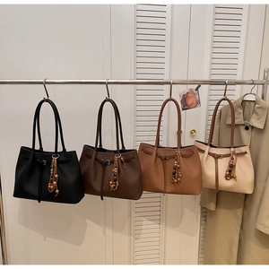 Detailed view of four leather tote bags in various colors hanging with tassel charms