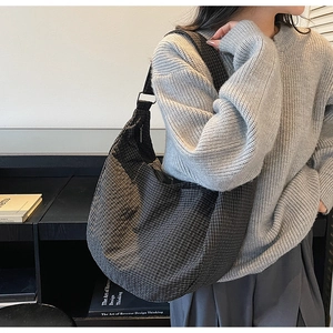 Side view of large grey checkered crossbody dumpling bag shown on a model