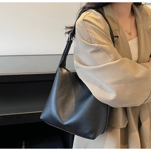Close-up of black lychee grain leather bucket bag with silver buckle and wide strap