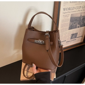 Detail of dark brown pebble leather bucket bag with silver twist-lock and slim strap