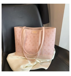 Detail of pink monogram tote bag with rabbit pattern and gold logo on black leather chair