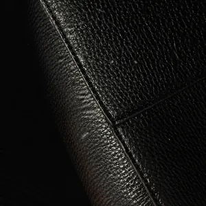 Nahaufnahme von schwarzem Leder mit Lychee-Narbung und robuster Naht an der Eimertasche