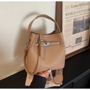 Detail of lychee pattern leather texture and silver buckle on tan bucket bag