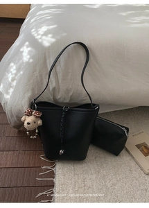 Dettaglio borsa a secchiello in pelle martellata nera con ciondolo a orso e pochette