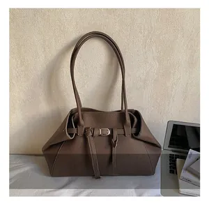 Detail of dark brown leather shoulder bag with buckle strap on an office desk