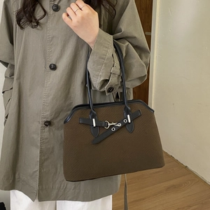 Brown textured tote bag with black leather straps and gold buckle detail on a model