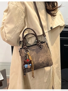 Retro brown bucket bag with plush bear charm and woven strap details for women