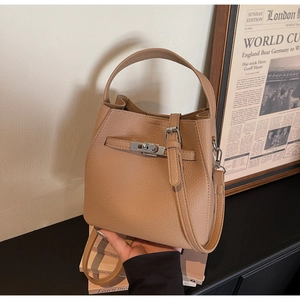Detailed view of brown litchi leather bucket bag with silver lock and adjustable strap