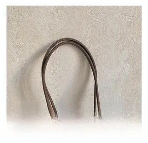 Detail view of smooth leather handle and metal buckle on dark brown tote bag