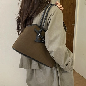 Retro deep brown canvas tote bag with black leather straps shown on model shoulder