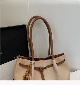 Detail of canvas tote bag with brown leather handles and wooden bead charm decoration