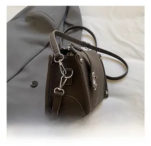 Detailed view of dark brown pebbled leather texture and silver metal rivets on a bag