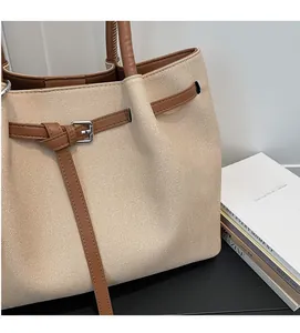 Close-up of canvas tote with leather straps and metal buckle detail for casual wear