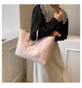 Detail view of pink tote bag with rabbit print and flat shoulder straps worn by model