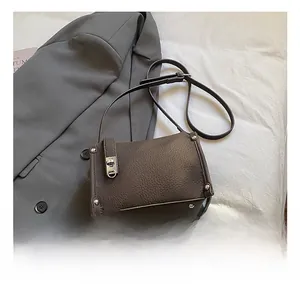 Macro shot of dark brown lychee leather texture and silver rivets on a vintage crossbody bag
