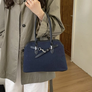 Detail of dark blue textured fabric handbag with leather straps and silver hook closure