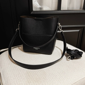 Detail einer schwarzen Beuteltasche aus Leder mit Kieselprägung auf weißem Hocker