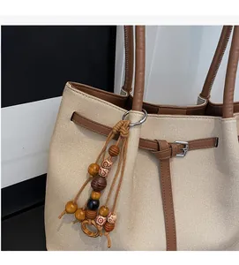 Close-up of canvas tote bag texture with brown leather straps and vintage wooden bead charm