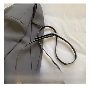 Detail of adjustable leather strap and silver metal buckle on brown lychee grain bag