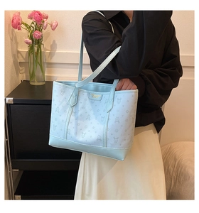 Detail of light blue tote bag with rabbit monogram and gold brand name logo plate