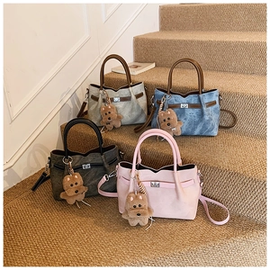 Close-up of matte textured tote bags with metal turn-lock and plush puppy charms