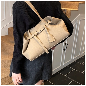 Detail of beige lychee grain leather tote bag worn by a model on a black knit sweater