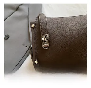 Detailed view of dark brown pebbled leather texture with silver metal buckle on a handbag