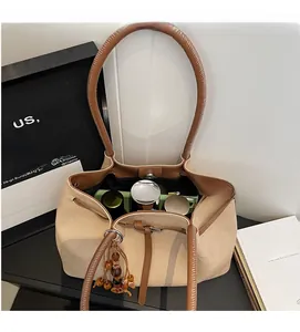Detail of canvas tote bag showing spacious interior filled with cosmetics and wood bead tassel
