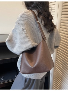 Minimalist dark brown lychee leather tote bag worn over the shoulder for a chic autumn look