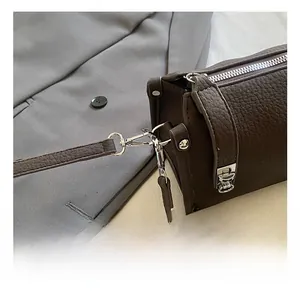 Detailed shot of silver hardware and litchi texture leather on dark brown Boston bag