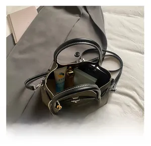 Internal capacity of green bucket bag showing notebook, phone, perfume, and cosmetics