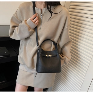 Detail of black lychee grain leather bucket bag with silver turn-lock and slim handle