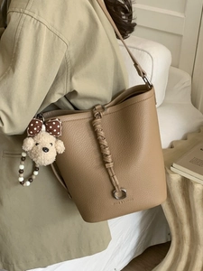Secchiello chic cachi in pelle litchi con cinturini intrecciati e ciondolo di peluche