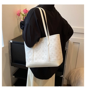 Detail of white tote bag with rabbit monogram print worn by a model in a minimalist room