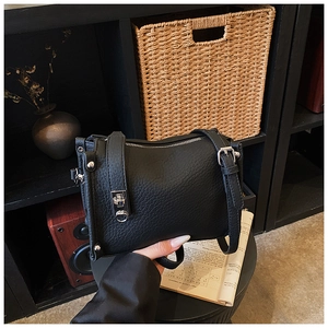 Detailed view of black lychee grain leather handbag with silver hardware and rivets