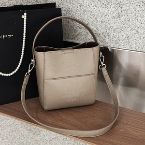 Detail der taupefarbenen Eimer-Tasche aus Lychee-Leder mit silbernen Beschlägen
