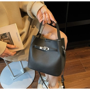 Detail of black pebbled leather bucket bag with silver twist lock and slim shoulder strap