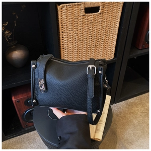 Close-up of black lychee grain leather texture and silver metal hardware details