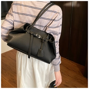Detail of black pebbled leather tote bag featuring buckle strap and chic side-view profile