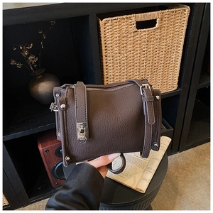 Close-up of lychee grain leather texture and silver hardware on dark brown bag