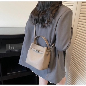 Detail of taupe pebbled leather bucket bag with metallic buckle and detachable strap