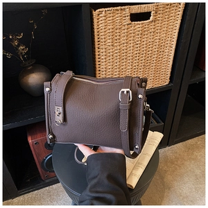 Close-up of dark brown lychee grain leather bag with silver hardware and turn-lock