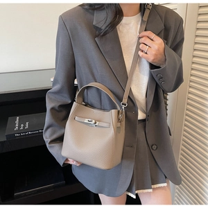 Detail of taupe litchi grain leather bucket bag with metallic twist lock and handle